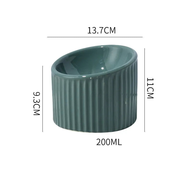 Dark green ceramic elevated cat bowl with tilted design on a wooden surface.