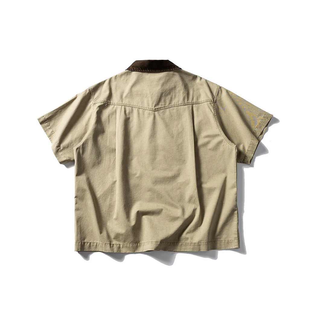 Washed khaki loose-fit cotton overalls shirt with short sleeves on a hanger.