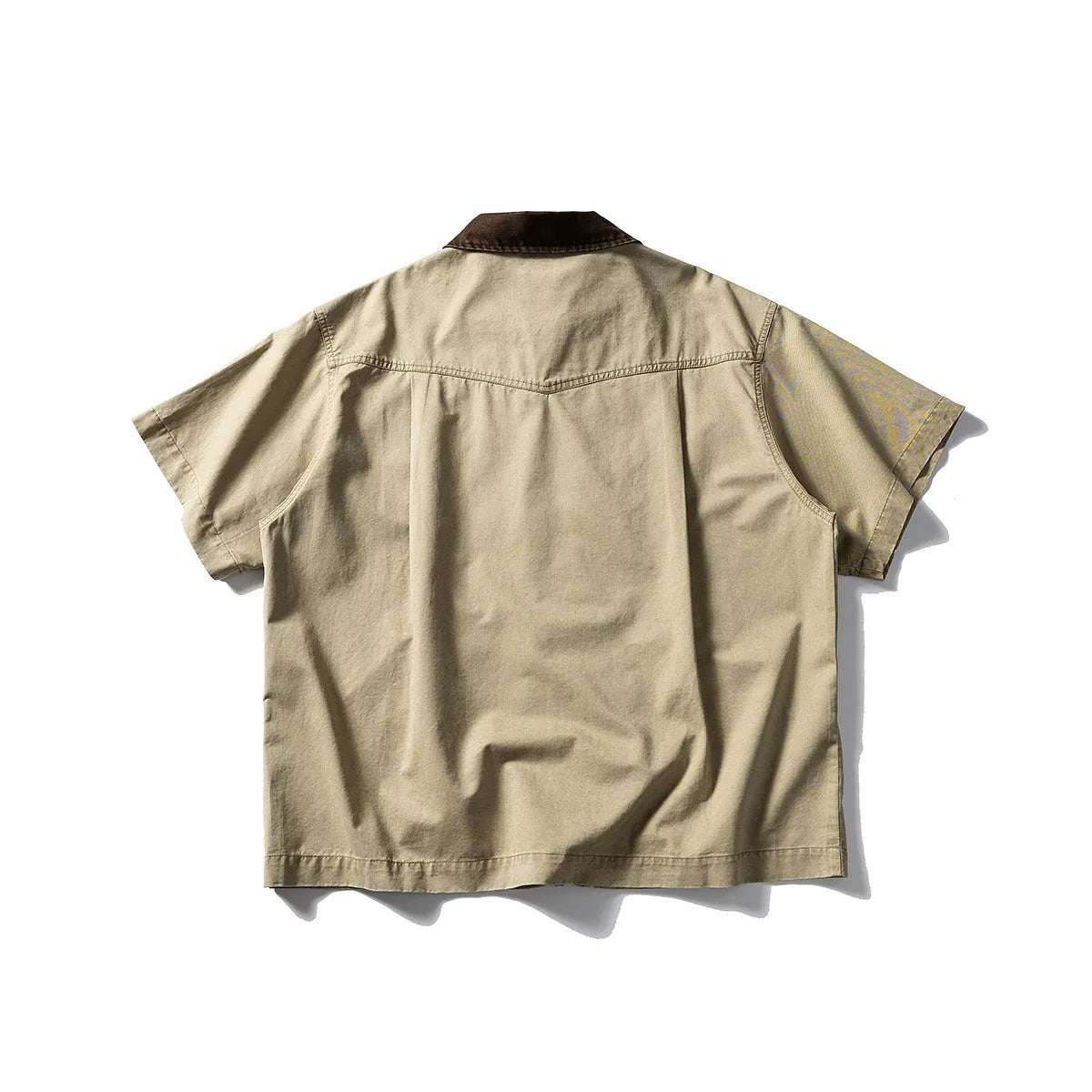 Washed khaki loose-fit cotton overalls shirt with short sleeves on a hanger.
