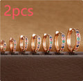 A pair of round gold-coloured stud earrings with a geometric perforated design and central zircon stone.