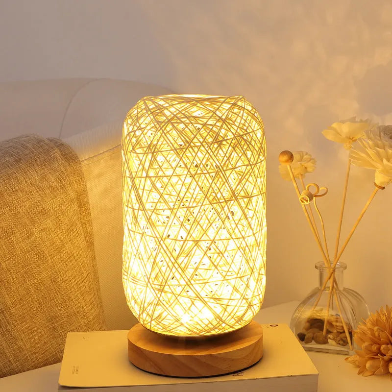 Handmade brown hemp rope spherical desk lamp with a solid wood base on a desk.