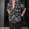 Man's loose fit black short sleeve shirt with floral pattern, worn open in cardigan style.