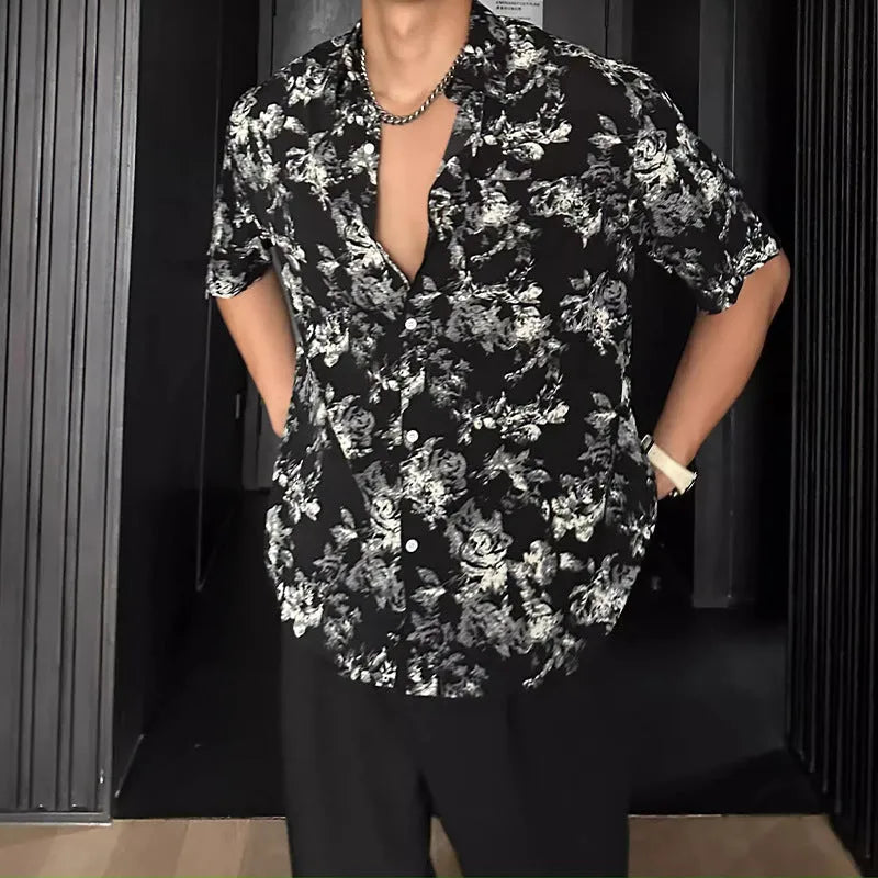 Man's loose fit black short sleeve shirt with floral pattern, worn open in cardigan style.
