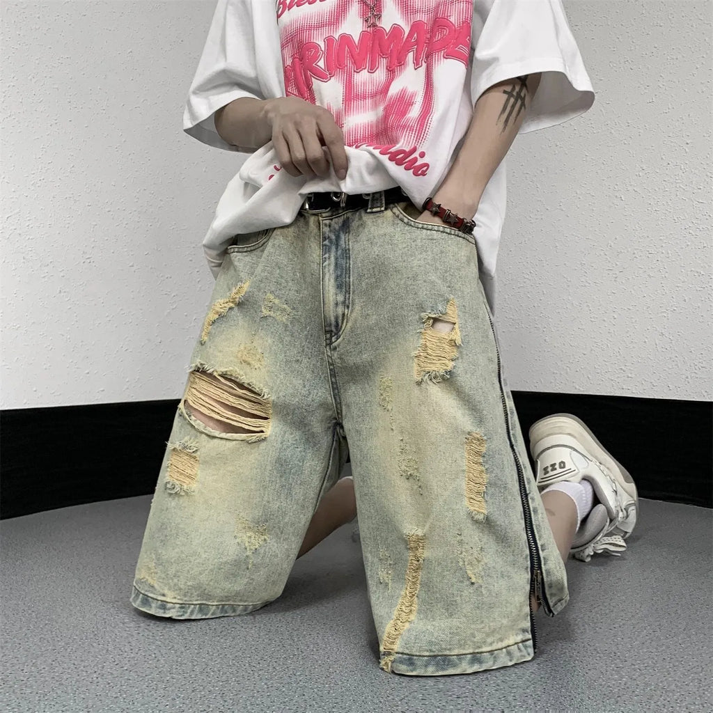 Men's blue retro denim shorts with yellow mud distressing, rips, button fly, and a loose fit.