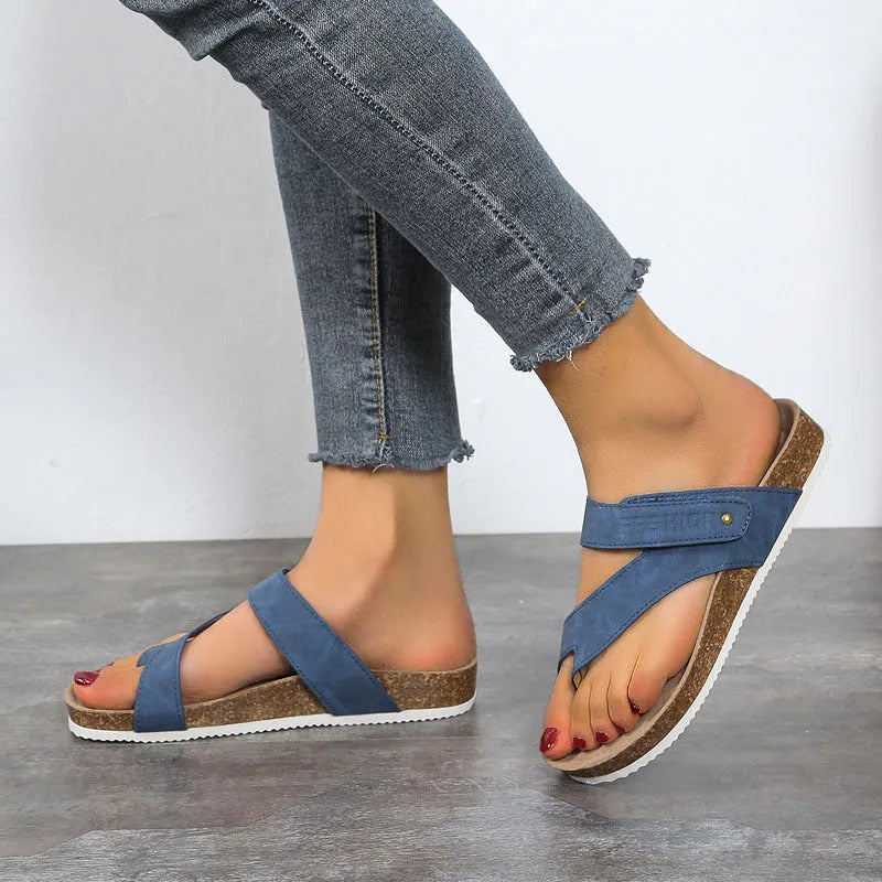 Thick-soled blue flip-flops with flat toe ring design on beach background