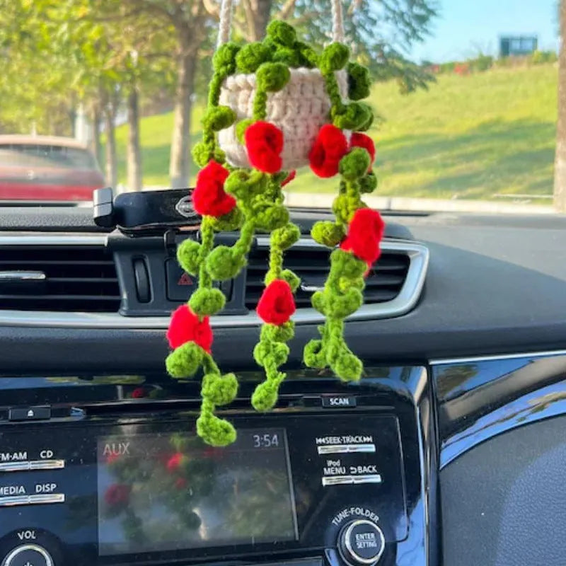 Green and white crochet wool car plant decoration with hanging rope on car dashboard