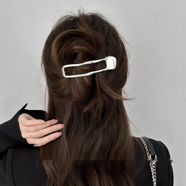 Golden zinc alloy hair barrette in an arc shape on a white background
