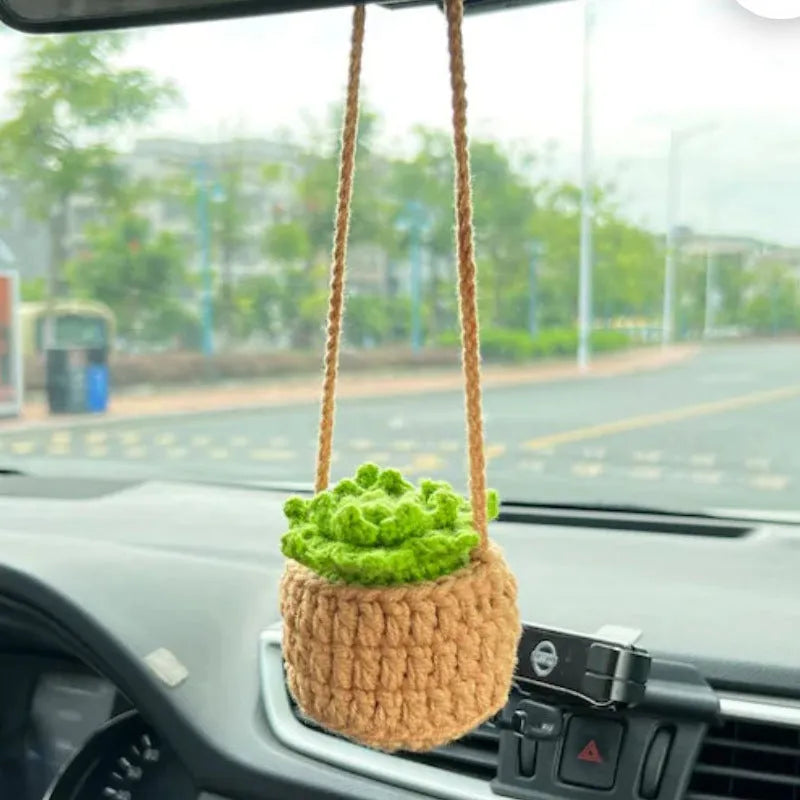 Green and white crochet wool car plant decoration with hanging rope on car dashboard