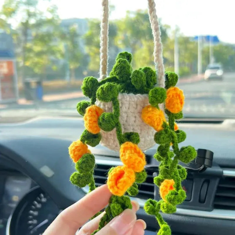 Green and white crochet wool car plant decoration with hanging rope on car dashboard