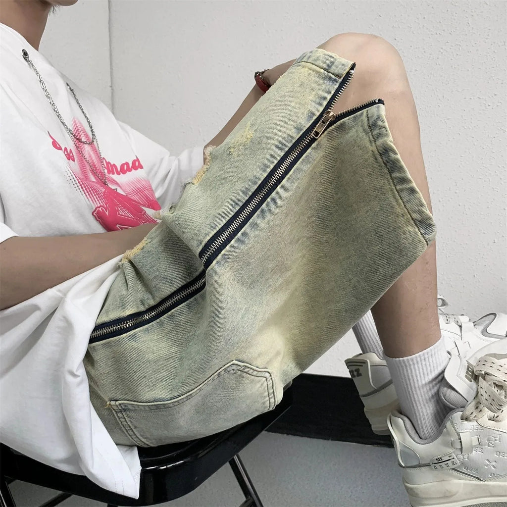 Men's blue retro denim shorts with yellow mud distressing, rips, button fly, and a loose fit.