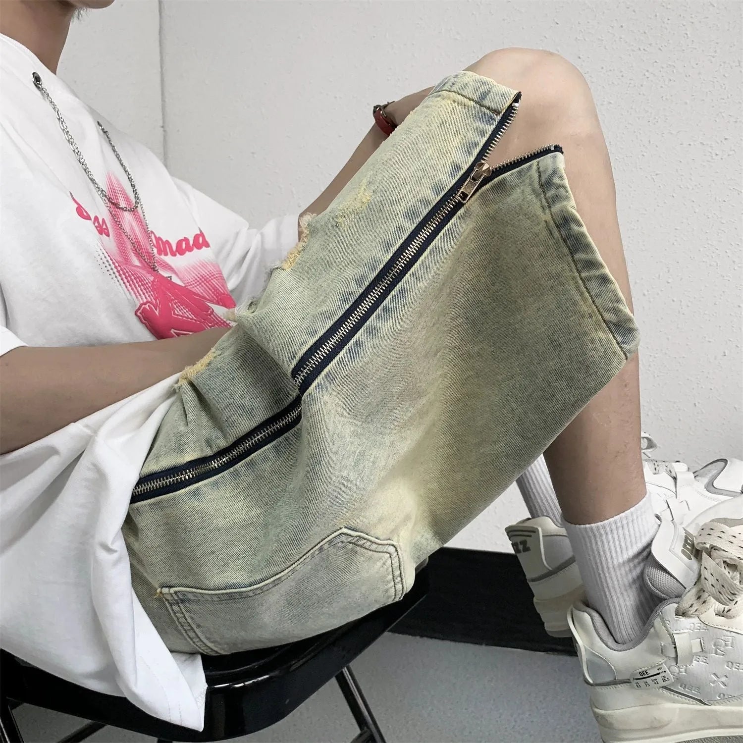 Men's blue retro denim shorts with yellow mud distressing, rips, button fly, and a loose fit.
