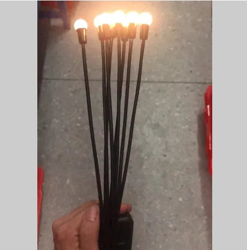 Solar-powered LED firefly lawn light with ground stake inserted in grass