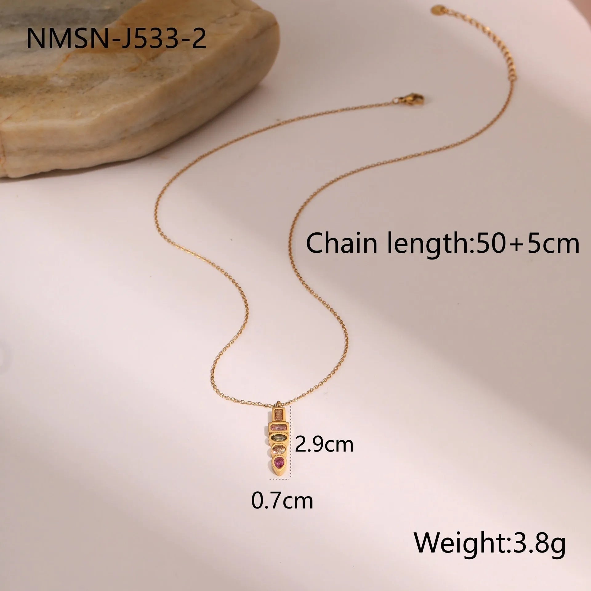 Geometric gold plated zircon jewellery set showing necklace, ring, and earrings on a grey background.