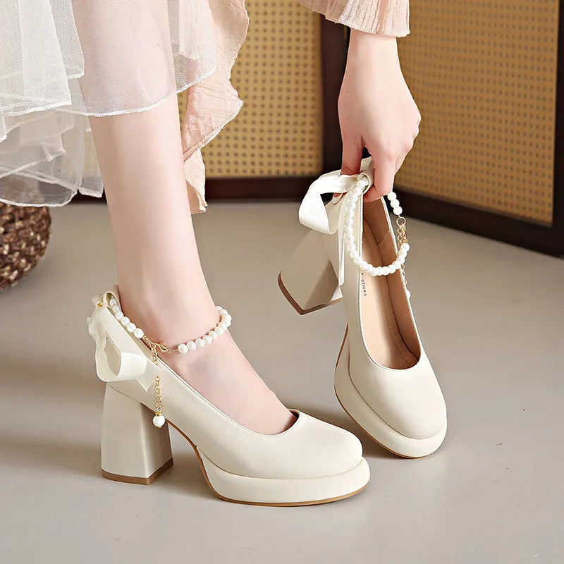 Beige women's Mary Jane shoes with a chunky heel, round toe, and ankle strap with a pearl and buckle.