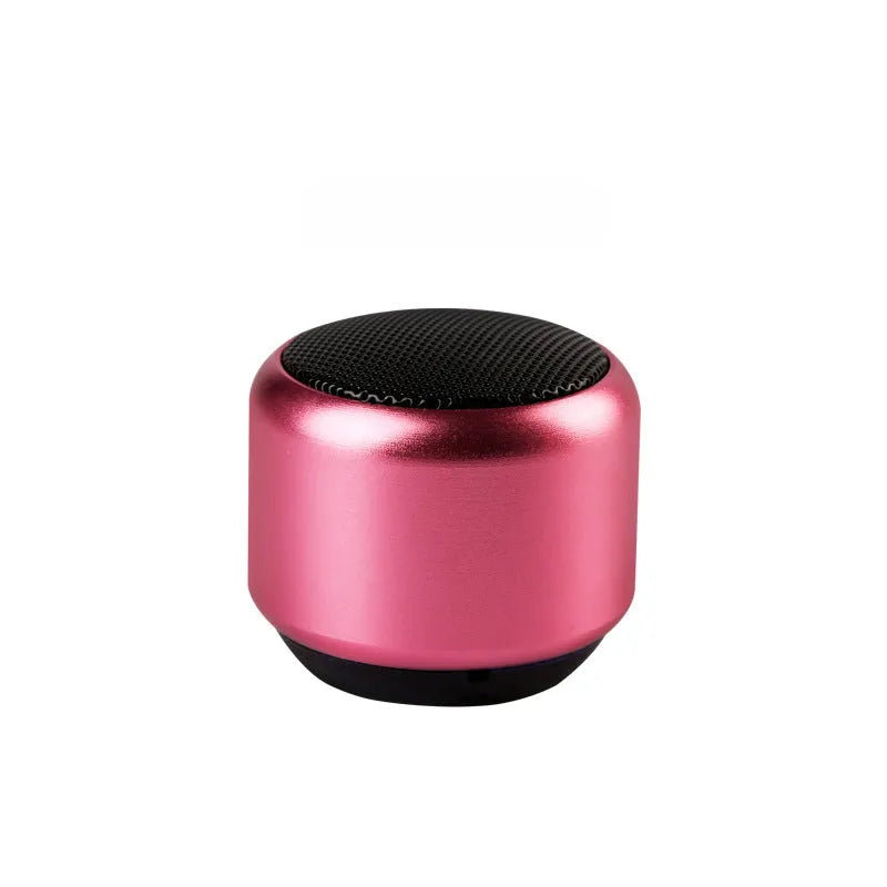 A small portable Bluetooth speaker shown in one of four colour options: black, blue, gold, or pink.