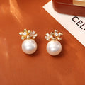 Pair of geometric round pearl and zircon stud earrings in gold plated finish on copper base