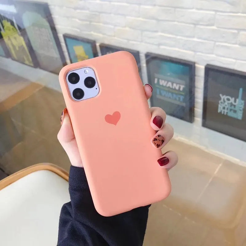 Solid colour silicone phone case for iPhone, shown in dark green, on a wooden surface.