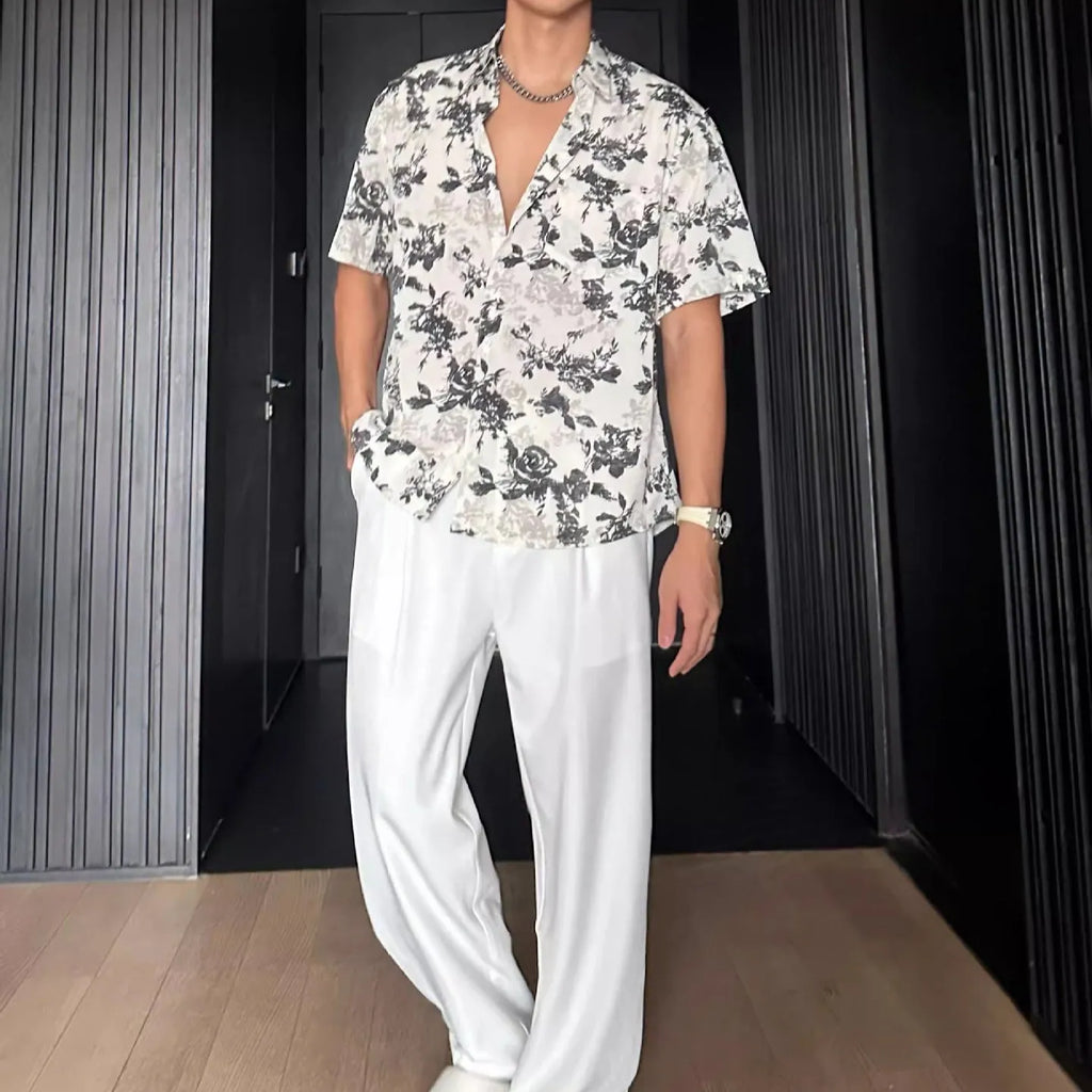 Man's loose fit black short sleeve shirt with floral pattern, worn open in cardigan style.