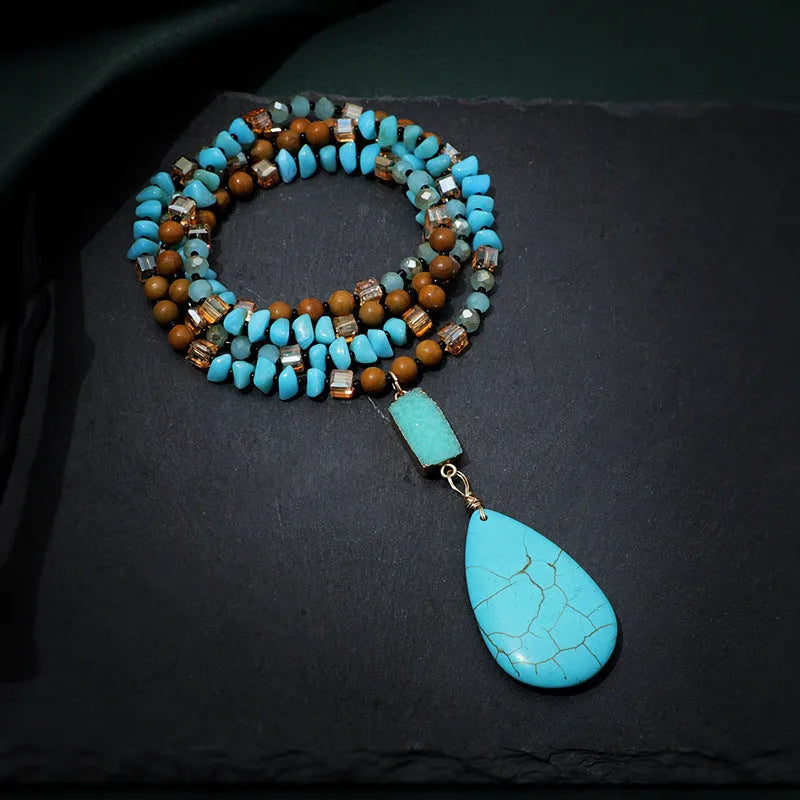 Turquoise blue water drop pendant necklace with geometric shapes on a long ball bead chain.