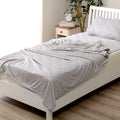 Blue and grey cooling blanket with Japanese Q-Max fibres on a bed.