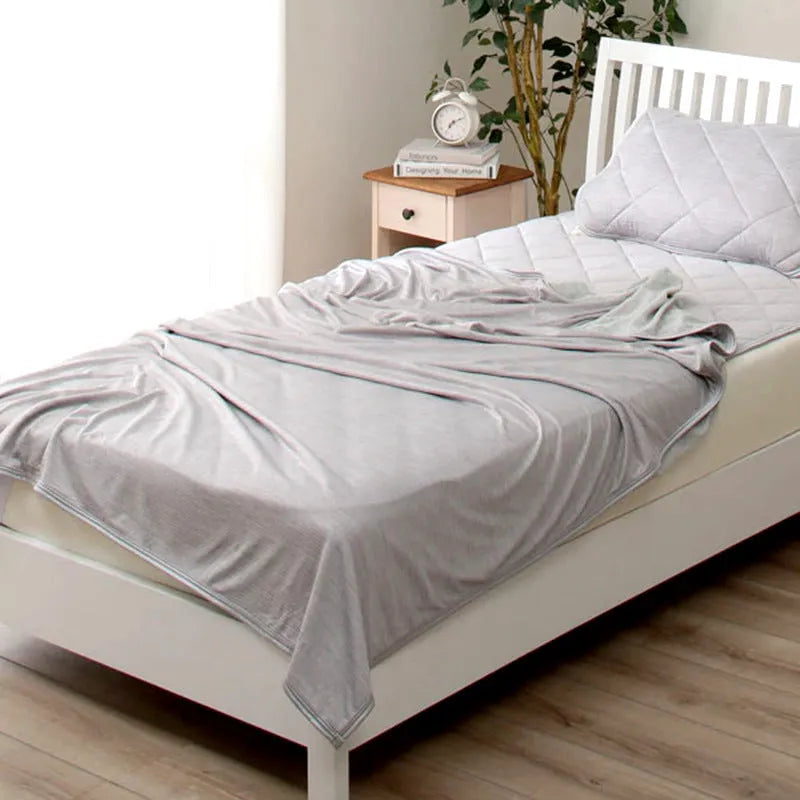 Blue and grey cooling blanket with Japanese Q-Max fibres on a bed.