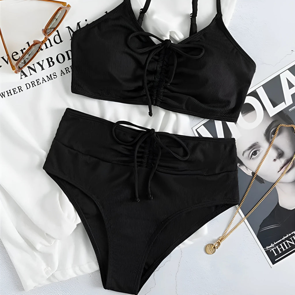 Black high-waisted bikini swimsuit for women with sleeveless top and shorts on a neutral background.