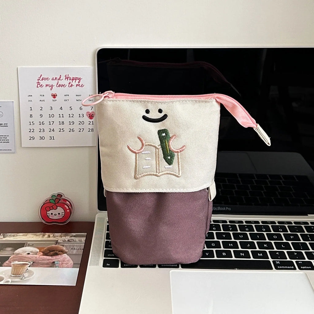 Brown and green cartoon-style collapsible Oxford cloth pencil case showing zip and 17x14cm size.