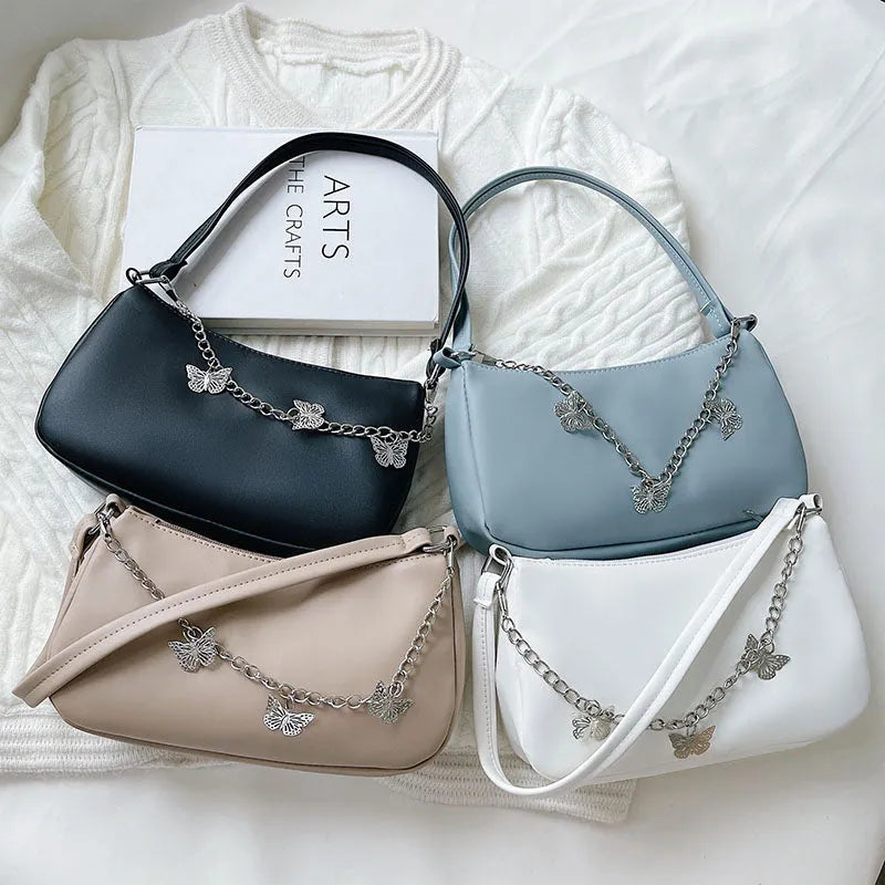 Square black PU leather crossbody bag with a butterfly chain strap and external structured pocket.