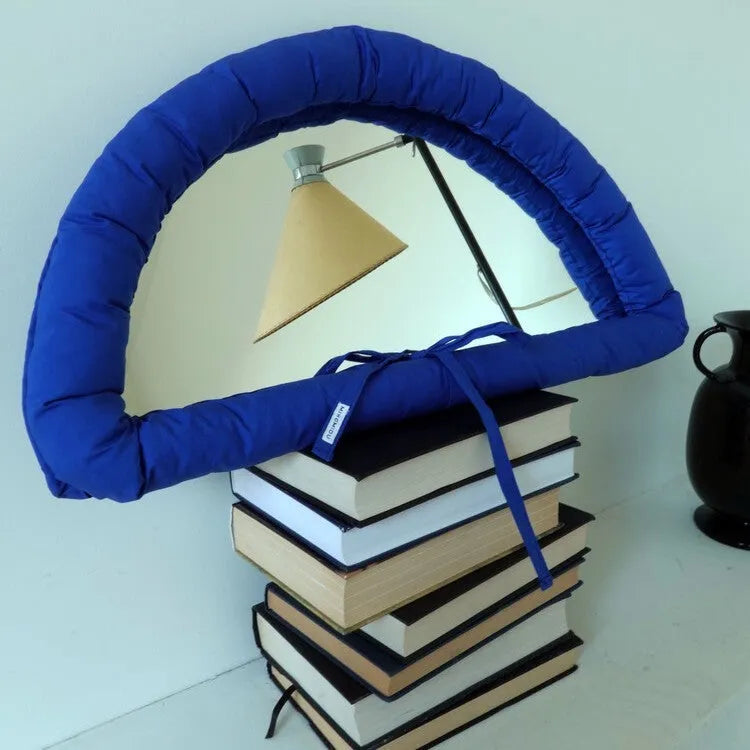 Rectangular white fabric mirror with soft filling hanging on a wall