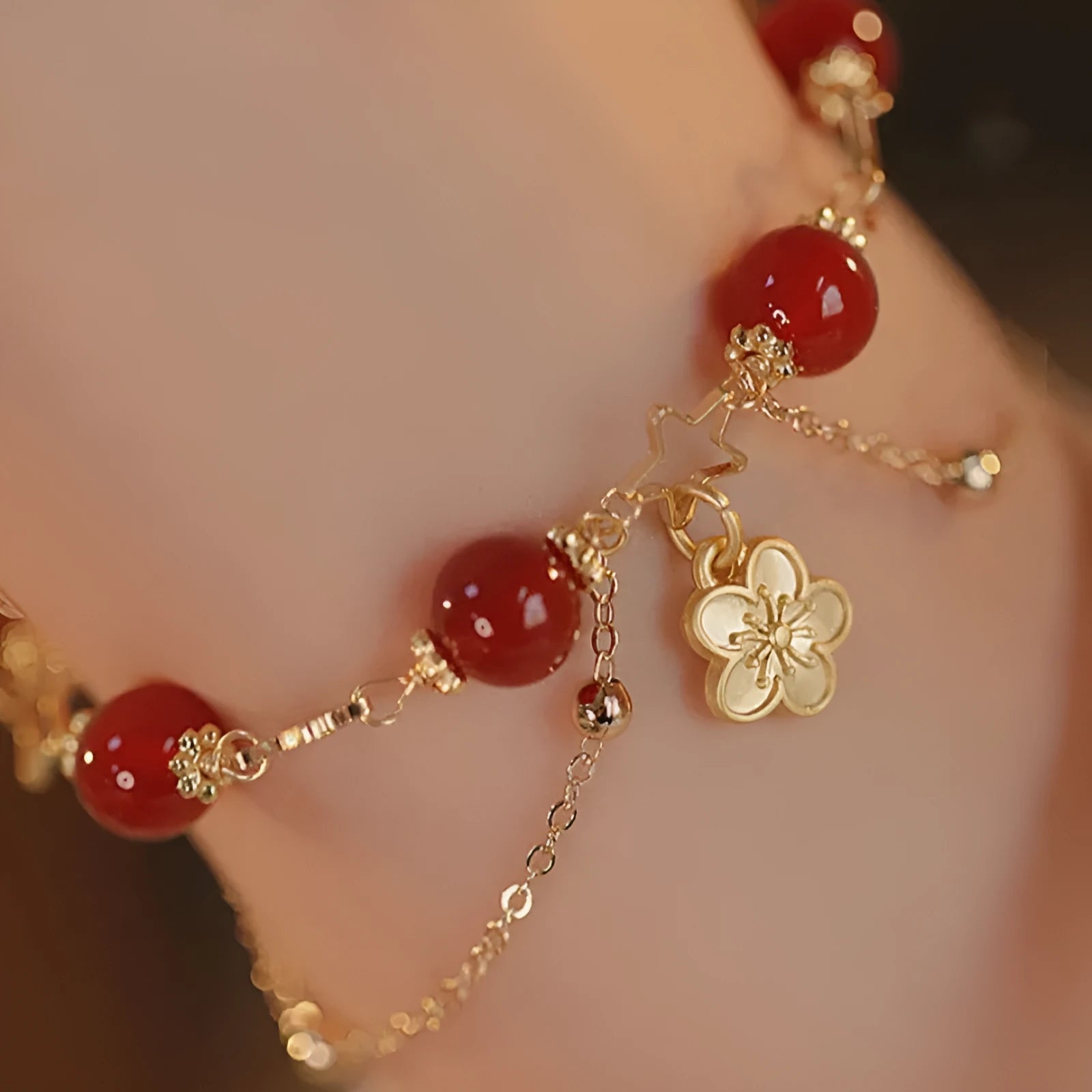 Red agate double layer women's bracelet with peach blossom design on adjustable string.