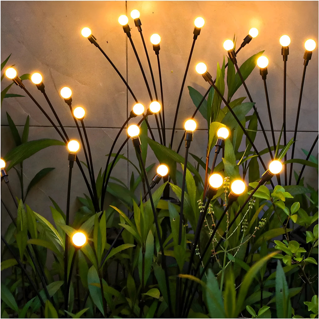 Solar-powered LED firefly lawn light with ground stake inserted in grass