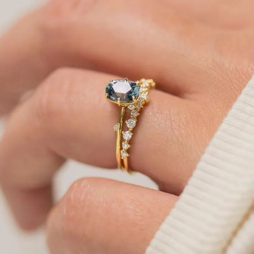 Gold-plated women's ring with green zircon stones and floral engraving on a white background.