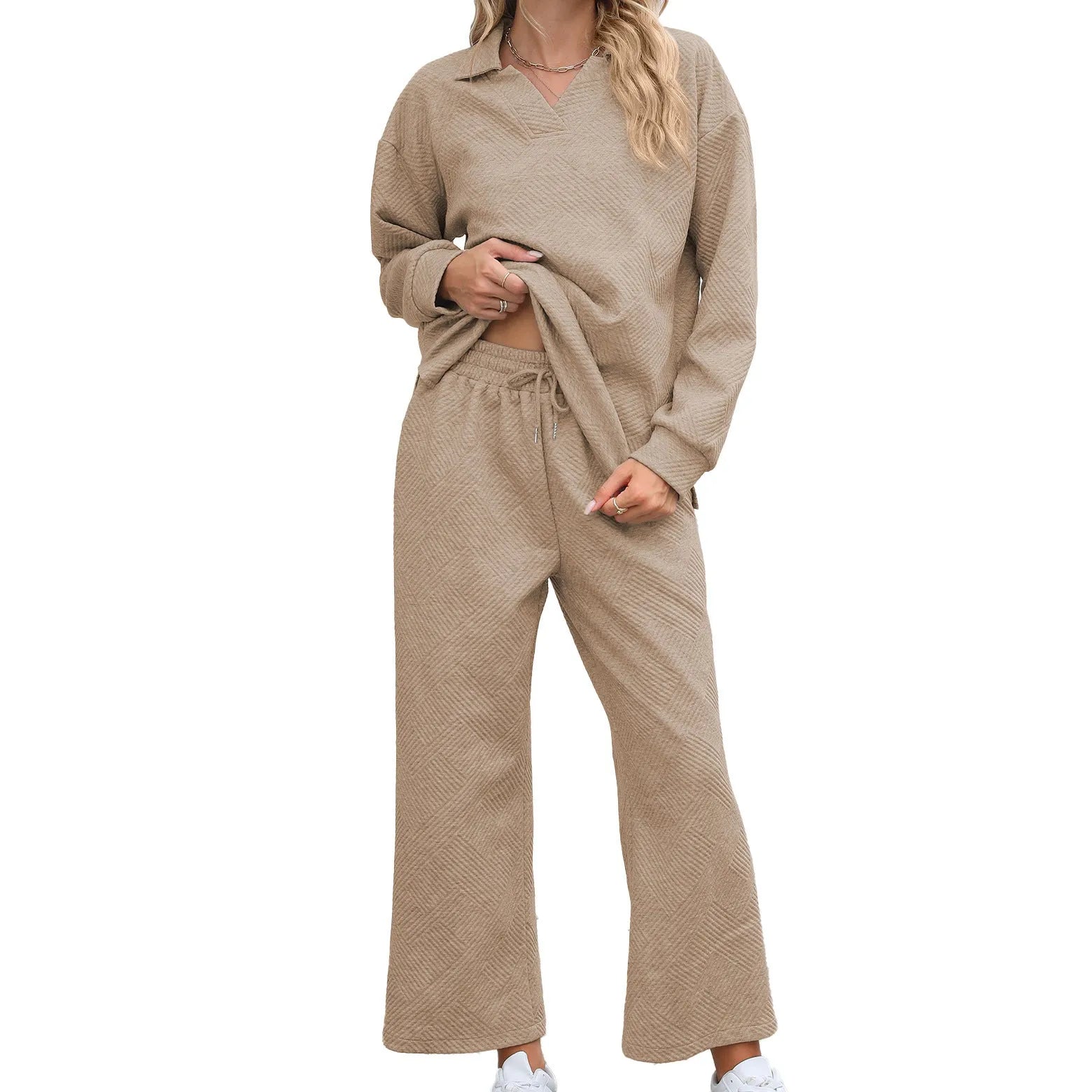Woman wearing a knitted jacquard long sleeve sweater and matching elastic waist cropped trousers in a solid colour.