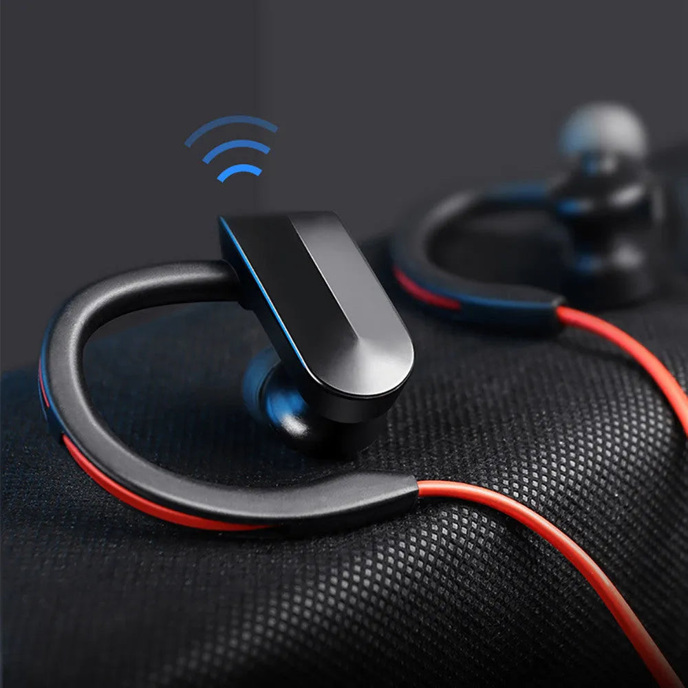 Black wireless Bluetooth neckband earphones with earpieces showing, placed next to a USB charging cable on a white background.