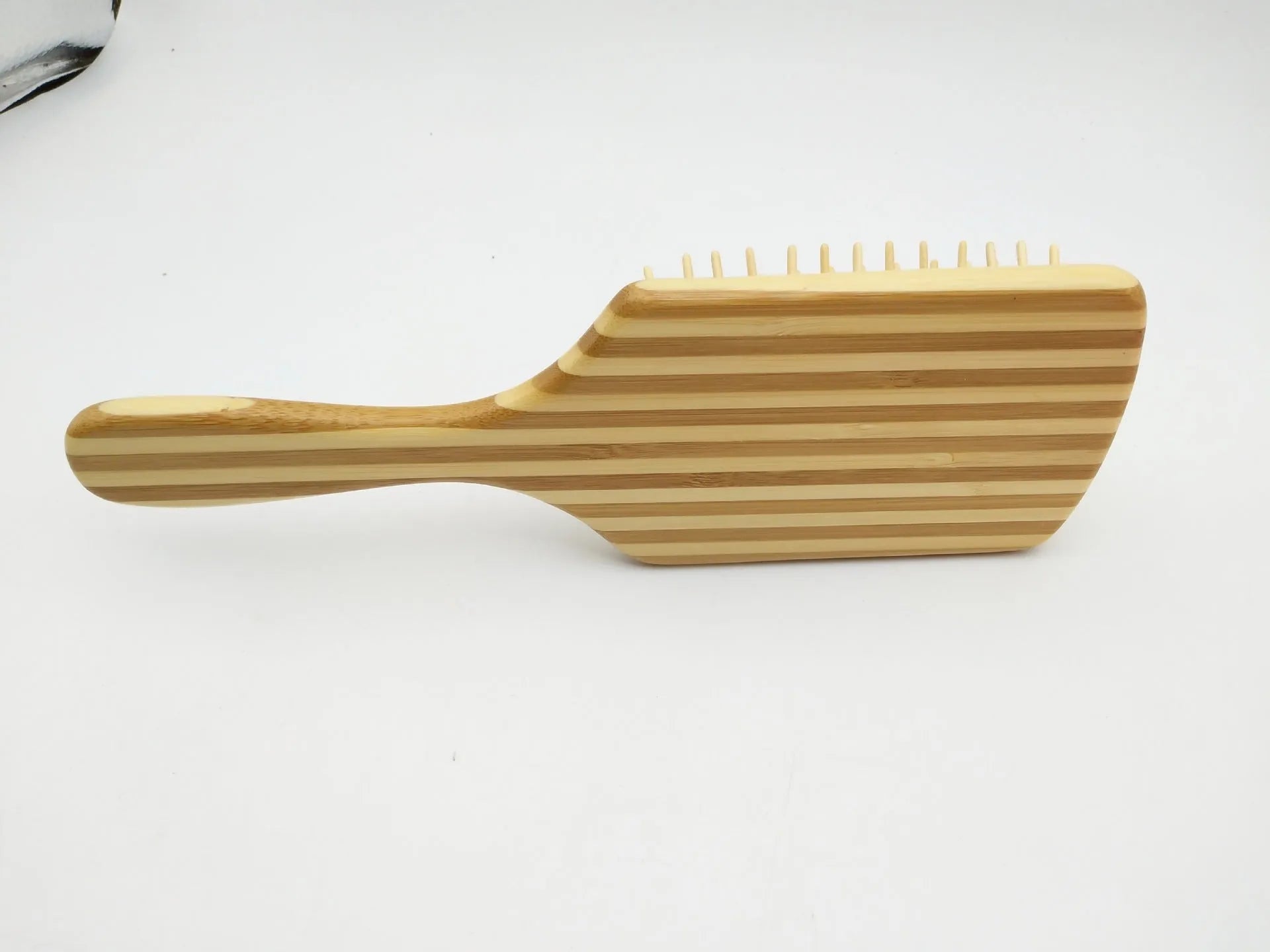 Natural bamboo scalp massage comb with round nylon teeth and rubber pad on neutral background