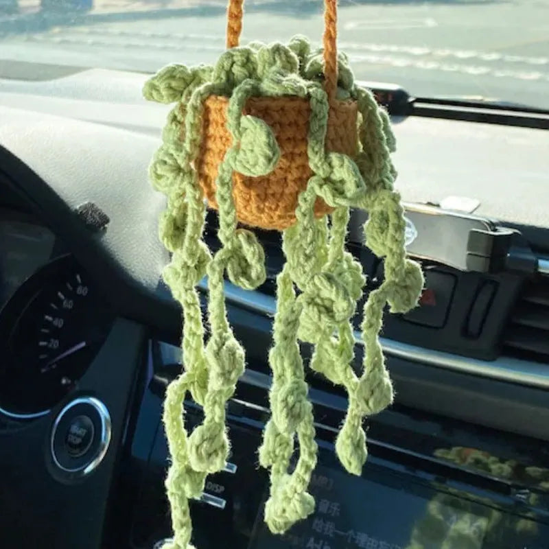 Green and white crochet wool car plant decoration with hanging rope on car dashboard