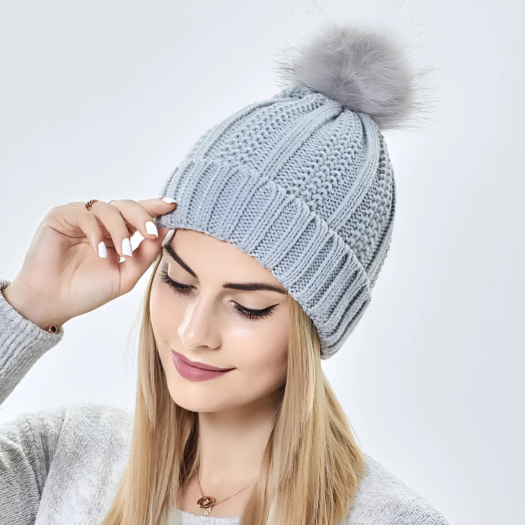 Women's black knit beanie with a faux fur pom pom and satin lining for hair protection