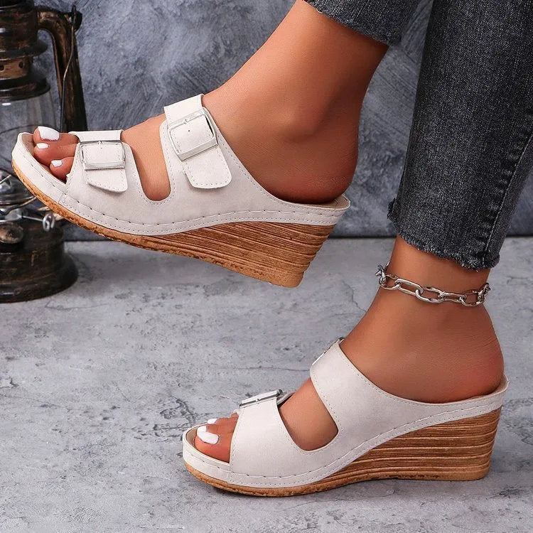 Women's creamy-white beach slippers with a decorative wedge buckle on the strap.