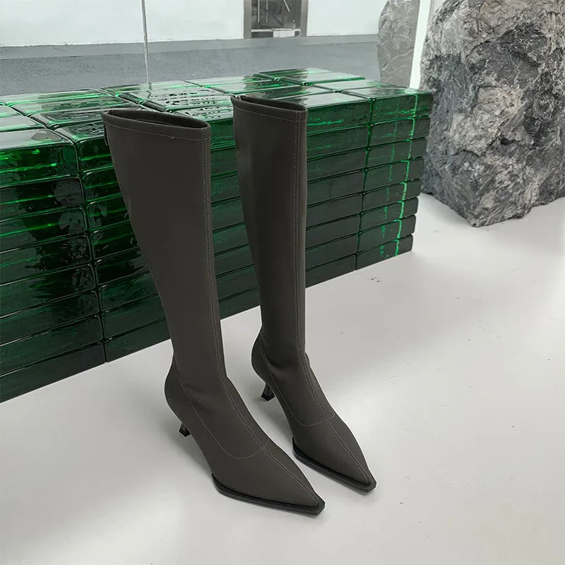 Black pointed toe women's below-the-knee boots with stiletto heel and back zipper fastening.
