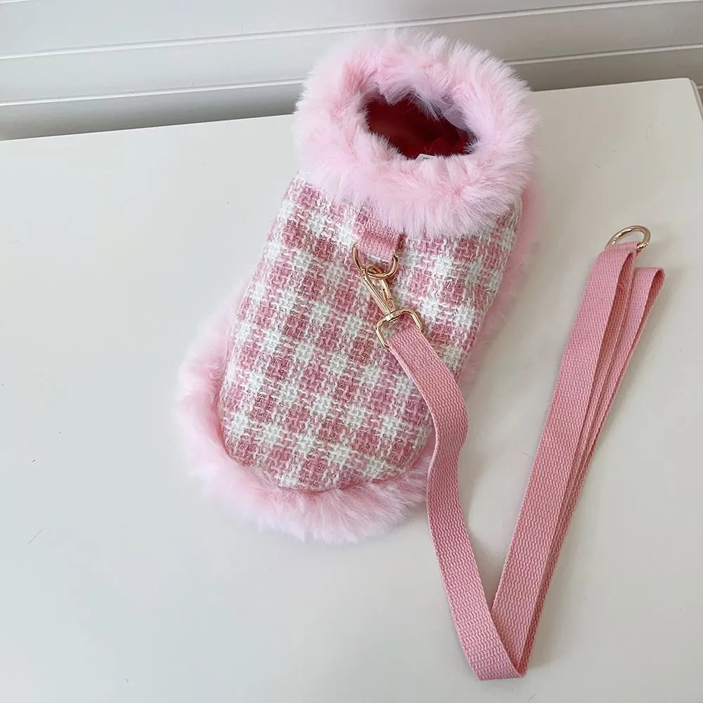 Pink cat wearing a beret and a cloak with a hand holding rope attached.