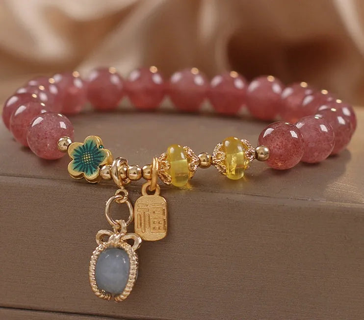 Red women's beaded bracelet made with natural strawberry quartz stones, alloy spacers, and rhinestone accents.
