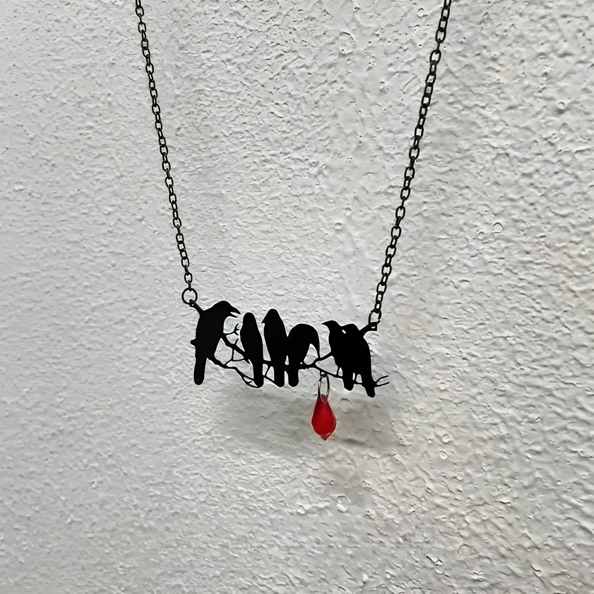 Black electroplated alloy crow pendant necklace on a cross chain for women.