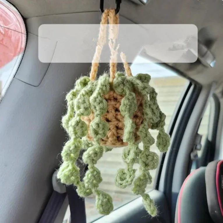 Green and white crochet wool car plant decoration with hanging rope on car dashboard