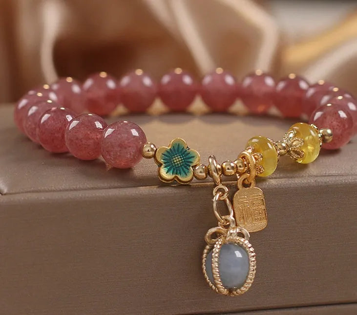 Red women's beaded bracelet made with natural strawberry quartz stones, alloy spacers, and rhinestone accents.