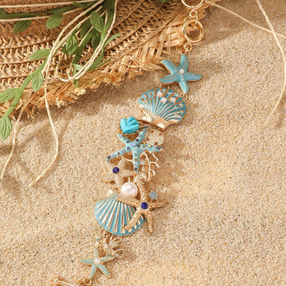Close-up of a women's alloy bracelet featuring a boat anchor, marine shell, and starfish charms in a coral blue colour.