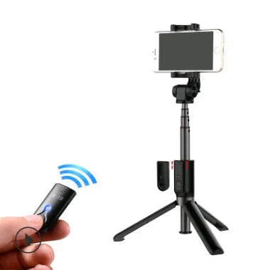 Black Bluetooth selfie stick tripod with extended rod, phone clamp, and deployed legs next to a smartphone