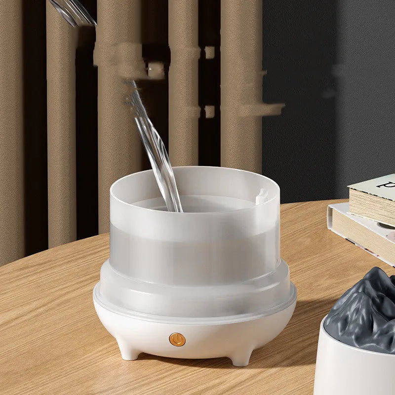Black volcano-shaped ultrasonic humidifier with USB cable on wooden desk emitting mist