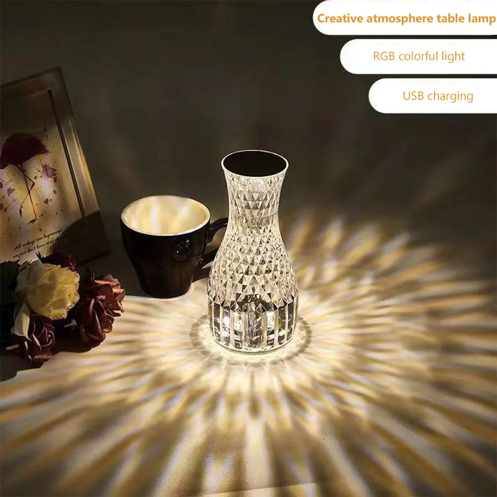 Clear plastic vase-shaped crystal bedside lamp with LED lights on a wooden table.