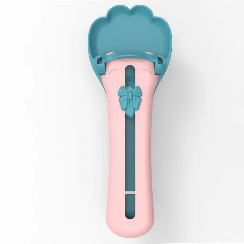 Green and pink pet food scooper spoon with squeezer handle and extruded feeder tip for dispensing treats.