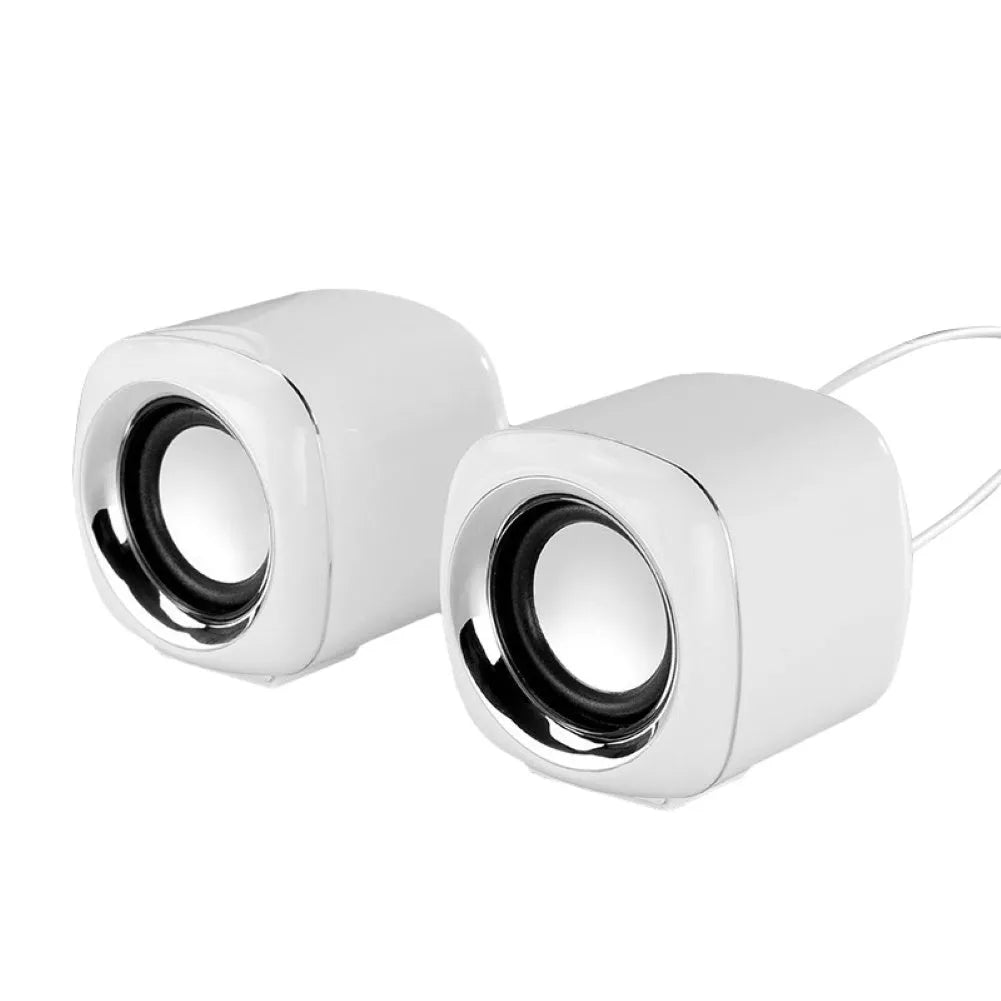 Pair of compact black wired desktop computer speakers with top volume scroll wheel next to a laptop.